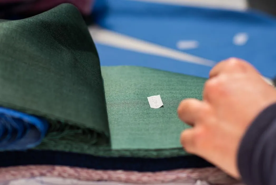 Mani al lavoro su un dettaglio di un pantalone verde