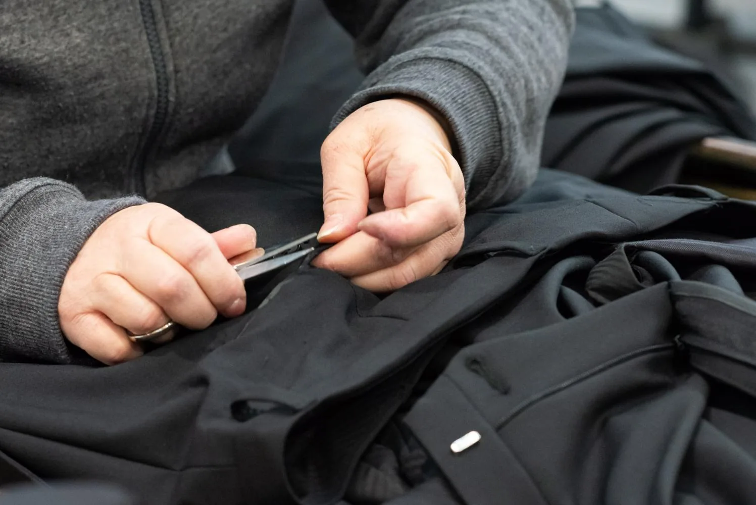 Mani che rifiniscono un pantalone scuro con le forbicine